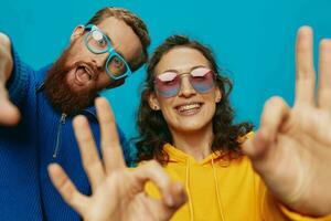 A woman and a man fun couple cranking and showing signs with their hands smiling cheerfully, on a blue background, The concept of a real relationship in a family. photo