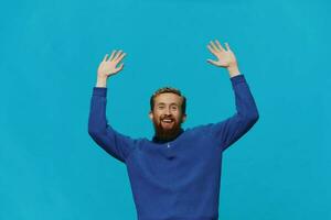 retrato de un hombre en un suéter sonrisa y felicidad, mano señales y símbolos, en un azul antecedentes. estilo de vida positivo, Copiar lugar. foto