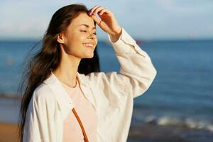 Woman portrait smile with teeth freedom vacation walking on the beach by the ocean in Bali sunset, happy journey and relaxation, sunset light, flying hair, the concept of change and emotional health photo