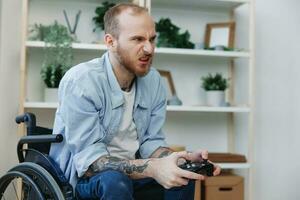 A man in a wheelchair gamer plays games with a joystick in his hands at home, anger and sadness from losing, copy space, with tattoos on his hands, health concept man with disabilities, real person photo