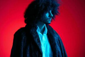 Fashion portrait of a man with curly hair on a red background, multinational, colored light, trendy, modern concept. photo