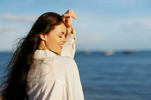 Woman beauty smile with teeth freedom on vacation walking on the beach by the ocean in Bali sunset, happy travel and vacation, sunset light, flying hair, skin and hair care concept in the sun photo