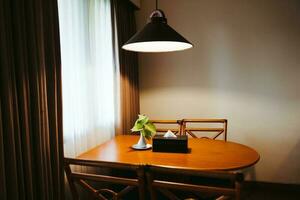 Dark home interior with wood dining table lit by lamp, evening light for dinner. photo