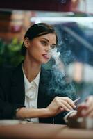 Stylish woman sits in a cafe at a table and smokes a cigarette, a bad habit photo