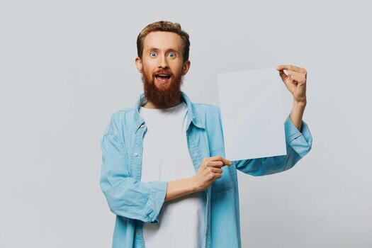 Portrait of an adult male on a gray background with a white sheet of paper in his hands for your design and text, layout, copy space, space for text, finger pointing photo