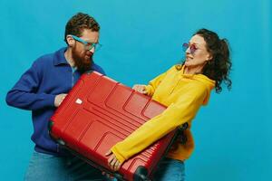 mujer y hombre sonrisa maletas en mano con amarillo y rojo maleta sonrisa divertido, en azul fondo, embalaje para un viaje, familia vacaciones viaje. foto