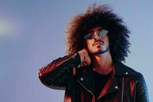 Portrait of a stylish man with curly hair on a blue background multinational, colored light, trendy glasses, modern concept. photo