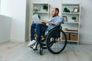 Man wheelchair freelancer working at laptop at home smile, working online, social networks and startup, copy space, integration into society, health concept man with disabilities, real person close-up photo
