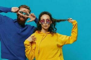 A woman and a man fun couple cranking and showing signs with their hands smiling cheerfully, on a blue background, The concept of a real relationship in a family. photo