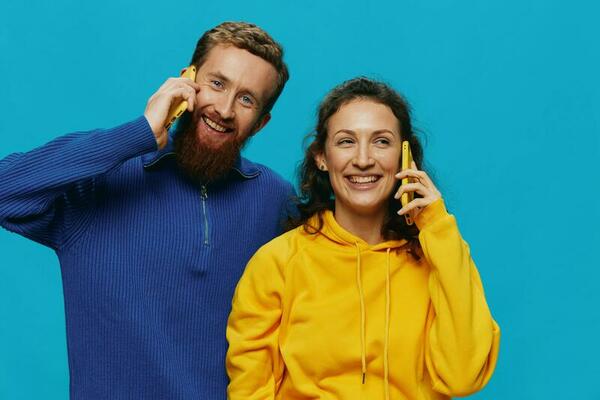 Woman and man cheerful couple with phones in their hands crooked smile cheerful, on blue background. The concept of real family relationships, talking on the phone, work online.