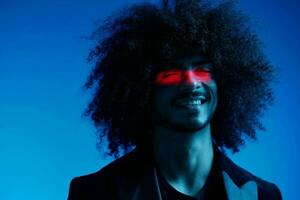 Fashion portrait of a man with curly hair on a blue background with a red stripe of light, multicolored light, trendy, modern concept. photo