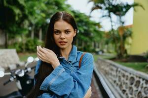 Portrait of a woman brunette smile with teeth walking outside against a backdrop of palm trees in the tropics, summer vacations and outdoor recreation, the carefree lifestyle of a freelance student. photo