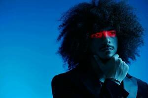 Fashion portrait of a man with curly hair on a blue background with a red stripe of light, multicolored light, trendy, modern concept. photo