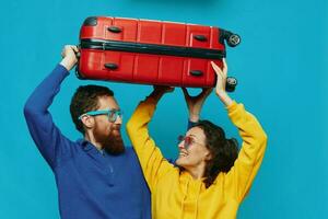 Woman and man smile suitcases in hand with yellow and red suitcase smile fun, on blue background, packing for a trip, family vacation trip. photo