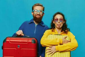 mujer y hombre sonrisa maletas en mano con amarillo y rojo maleta sonrisa divertido, en azul fondo, embalaje para un viaje, familia vacaciones viaje. foto