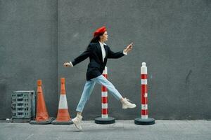 Fashion woman running down the street in front of the city tourist in stylish clothes with red lips and red beret, travel, cinematic color, retro vintage style, late to work, run. photo