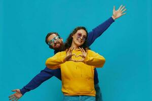 A woman and a man fun couple cranking and showing signs with their hands smiling cheerfully, on a blue background, The concept of a real relationship in a family. photo