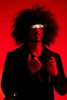 Fashion portrait of a man with curly hair on a red background, multinational, colored light, trendy, modern concept. photo