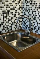 Clean sink with pouring water in the kitchen, metal faucet and sink in an old home interior. photo