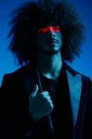 Fashion portrait of a man with curly hair on a blue background with a red stripe of light, multicolored light, trendy, modern concept. photo