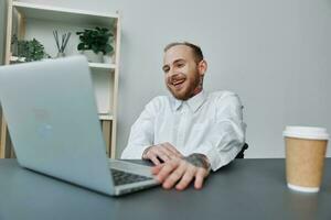 A man in a wheelchair, a businessman with tattoos in the office at a laptop, a coffee break, the concept of working a person with disabilities, freedom from social frames photo