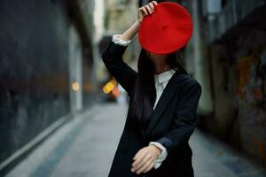 Moda mujer sonrisa con dientes y divertido turista en elegante ropa en chaqueta y rojo boina caminando abajo estrecho ciudad calle volador cabello, viajar, francés estilo, cinematográfico color, retro estilo. foto