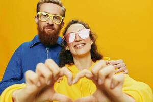 hombre y mujer Pareja sonriente alegremente y torcido con anteojos, en amarillo fondo, símbolos señales y mano gestos, familia disparar, recién casados. foto