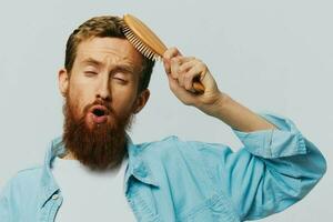 Portrait of a man with a massage comb in his hands, combing his hair and beard, hair loss problem photo