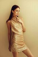 Beautiful woman in a gold glittery sequined dress poses in a stylish look for a Christmas disco night party photo