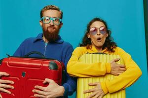 mujer y hombre sonrisa maletas en mano con amarillo y rojo maleta sonrisa divertido, en azul fondo, embalaje para un viaje, familia vacaciones viaje. foto