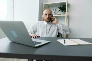 A man in a wheelchair businessman with tattoos in the office works, talking on the phone and smiling, integration into society, the concept of working a person with disabilities photo