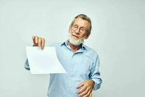 Portrait of happy senior man in a blue shirt and glasses a white sheet of paper cropped view photo