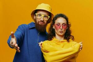 Woman and man smiling, suitcases in hand with yellow and red suitcase smiling merrily and crooked, yellow background, going on a trip, family vacation trip, newlyweds. photo