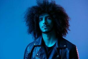 Portrait of fashion man with curly hair on blue background multinational, colored light, black leather jacket trend, modern concept. photo