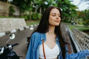 retrato de un mujer morena sonrisa con dientes caminando fuera de en contra un fondo de palma arboles en el zona tropical, verano vacaciones y al aire libre recreación, el despreocupado estilo de vida de un Lanza libre alumno. foto