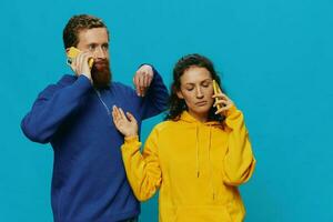 Woman and man cheerful couple with phones in their hands crooked smile cheerful, on blue background. The concept of real family relationships, talking on the phone, work online. photo