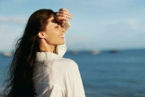 Woman beauty smile with teeth freedom on vacation walking on the beach by the ocean in Bali sunset, happy travel and vacation, sunset light, flying hair, skin and hair care concept in the sun photo