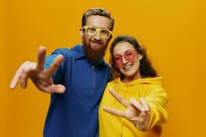 hombre y mujer Pareja sonriente alegremente y torcido con anteojos, en amarillo fondo, símbolos señales y mano gestos, familia disparar, recién casados. foto