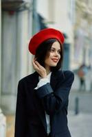 Moda mujer sonrisa primavera caminando en el ciudad en elegante ropa con rojo labios y rojo boina, viajar, cinematográfico color, retro Clásico estilo, urbano Moda estilo de vida. foto