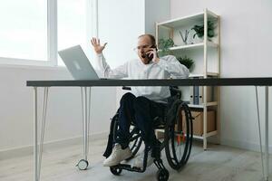 A man in a wheelchair a businessman with tattoos in the office works, talking on the phone, anger and aggression, integration into society, the concept of working a person with disabilities photo