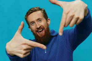 Portrait of a man in a sweater smile and happiness, hand signs and symbols, on a blue background. Lifestyle positive, copy place. photo