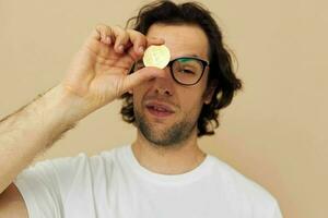 hermoso hombre en un blanco camiseta con bitcoin criptomoneda beige antecedentes foto