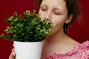 Young woman in green shorts flowerpot posing red background unaltered photo