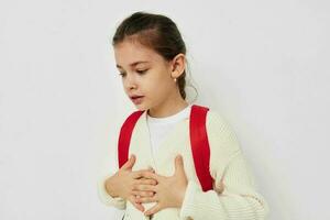 bonito joven Chica de escuela con rojo mochila posando estilo de vida inalterado foto