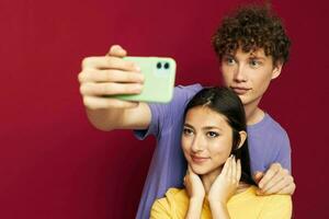 nice guy and girl in colorful T-shirts with a phone isolated background photo