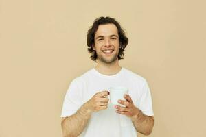 Attractive man with a white mug in his hands emotions posing beige background photo