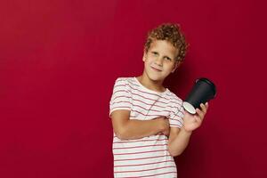 curly-haired boy in a striped t-shirt with a disposable glass photo