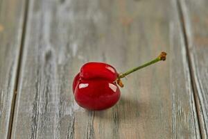 Nature's Oddity ugly, irregularly shaped cherry stands out against a rustic wooden backdrop photo