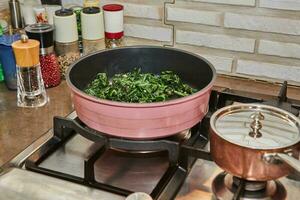 Sorrel is fried in frying pan in oil on gas stove photo