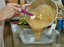 cocinero vierte el masa para haciendo cazuela desde berenjena y calabacín en dos colores dentro el molde foto